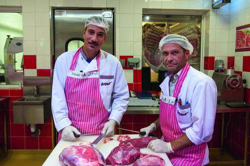 Ramadan Barakat, left, and Vincent Titeca work in the Eat Meat shop in the Meat Market at the Mushrif Mall. Mona Al-Marzooqi / The National