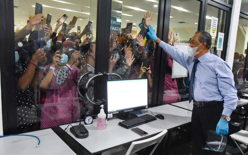 Malaysia’s Prime Minister Muhyiddin Yassin waving to people positive with Covid-19 coronavirus at a quarantine facility in Serdang, outside Kuala Lumpur. AFP