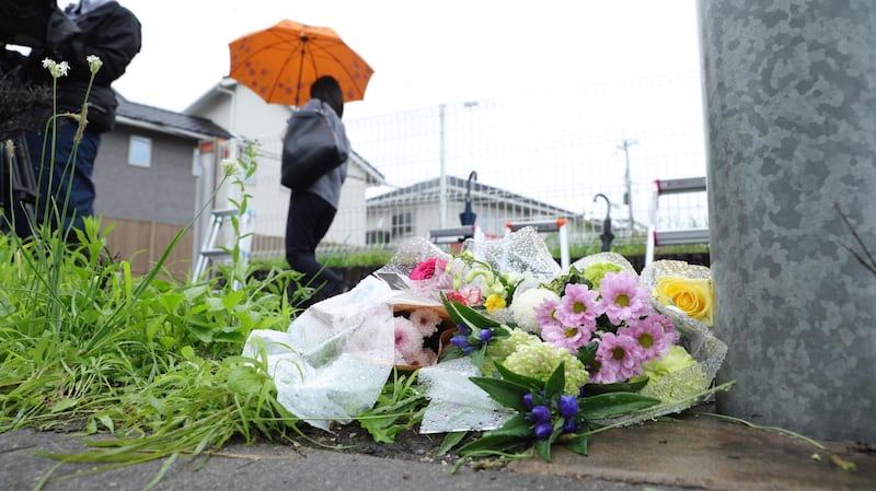 A woman stands next to flowers outside the scene where over 30 people died in a fire. AFP