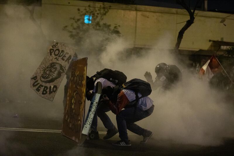 Demonstrators shield themselves as tear gas canisters are fired by police. Bloomberg
