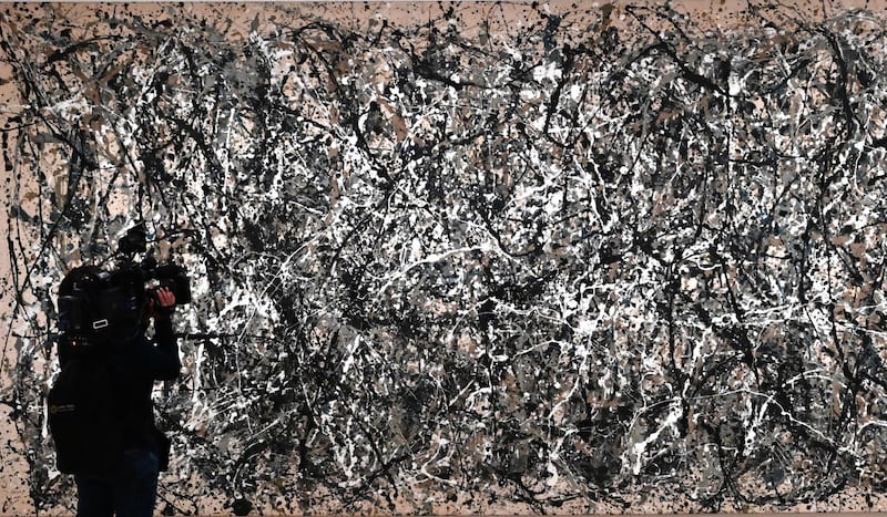 A member of the media looks at Jackson Pollock's "One: Number 31, 1950."
