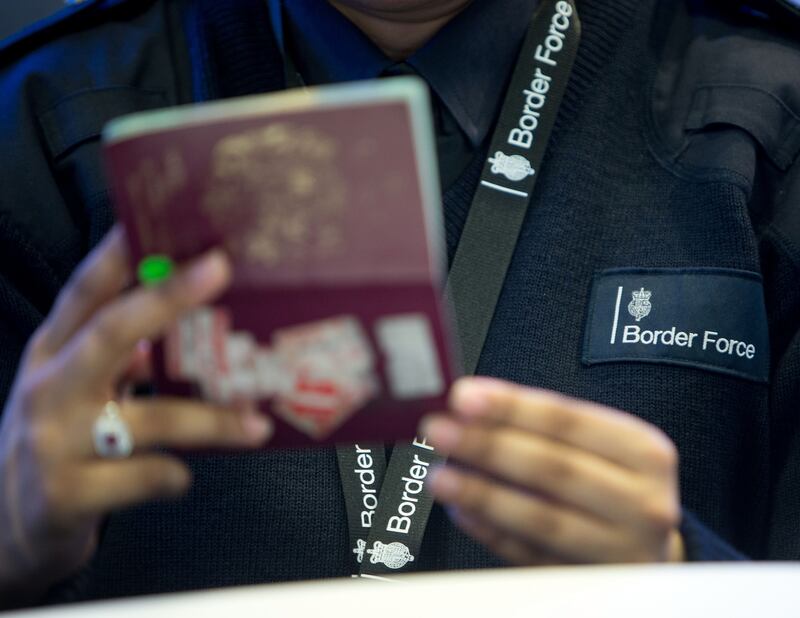 A Border Force officer checks a passport at Heathrow Airport. PA