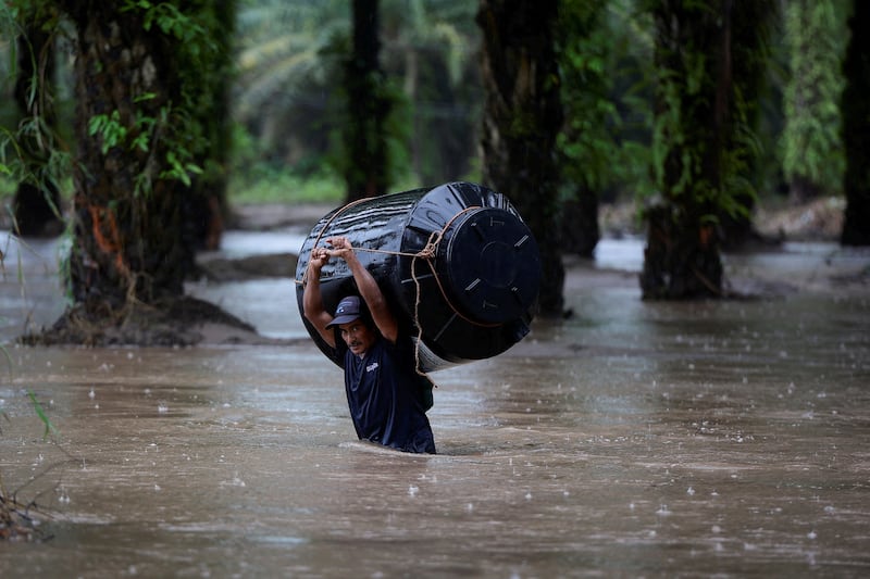A man carries an empty water tank through a flooded area after the impact of tropical storm Julia, in Progreso, Honduras, on October 9, 2022. Reuters