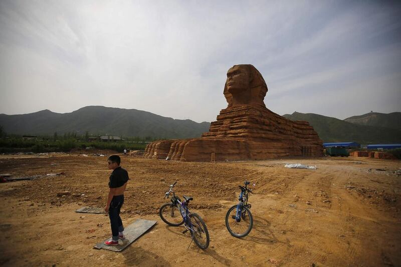 A man stands next to bicycles in front of a full-scale replica of the Sphinx, part of an unfinished theme park that will also accommodate the production of movies, television shows and animation, on the outskirts of Shijiazhuang, Hebei province in China. Reuters
