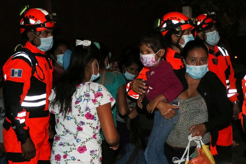 Handout picture released by Bomberos Volutarios shows Firefighters help evacuees settle in a temporary shelter in Santa Lucia Cotzumalguapa south Guatemala City on March 7, 2022.  - Some 370 people from a community based at the base of the Fuego volcano, in southwestern Guatemala, were evacuated on Monday following the increase in the volcanic activity of the colossus, the Civil Protection Agency reported.   AFP