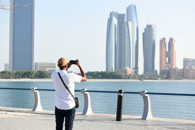 A tourist taking photos at the Corniche in Abu Dhabi. More than Dh1.1 billion has been provided for tourism developments in the emirate. Khushnum Bhandari / The National
