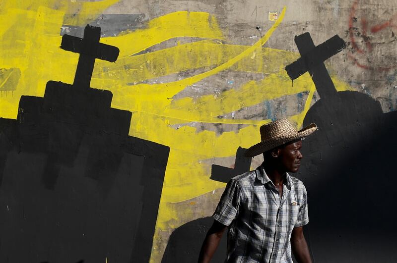 A man walks past a mural being painted by students from the National School of the Arts to express solidarity with those killed during a month of protests demanding the president's resignation in Port-au-Prince, Haiti.  AP