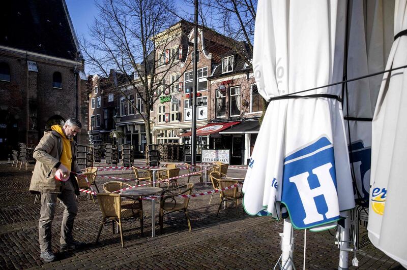 An official puts warning tape around tables and chairs set up at a cafe in Alkmaar, The Netherlands. A group of 65 regional departments of Koninklijke Horeca Nederland (KHN) have called on catering entrepreneurs throughout the Netherlands to re-open their businesses in protest against restrictions. AFP