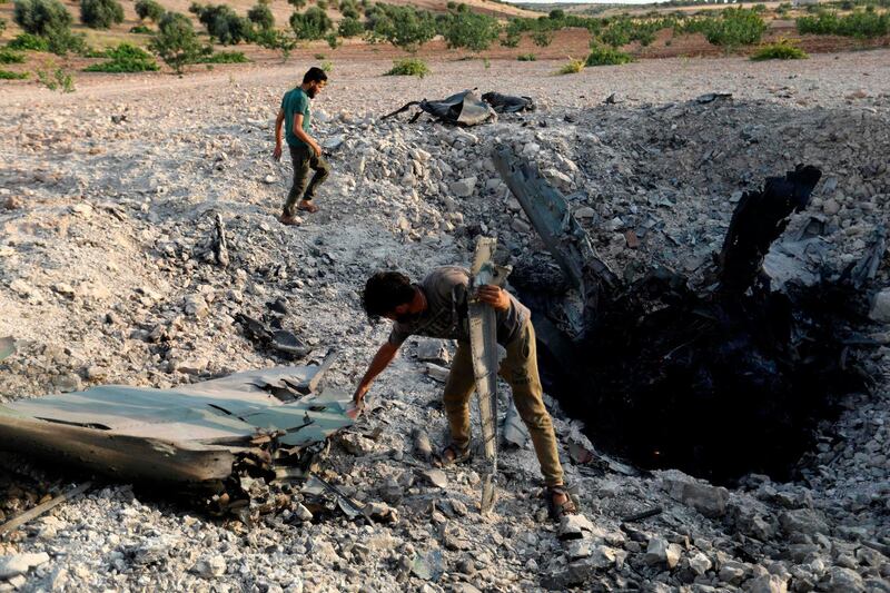 Rebel fighters gather near the remains of a downed regime warplane near the militant-held town of Khan Sheikhun. AFP