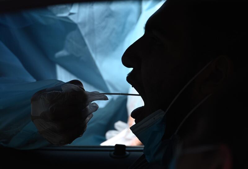 A healthcare worker collects a test sample from a motorist at a drive-through coronavirus testing center at MTO Shahmaghsoudi School of Islamic Sufism in Los Angeles, California. AFP