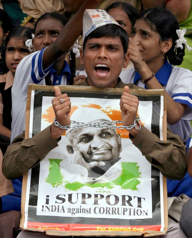 A supporter of veteran Indian social activist Anna Hazare wearing a handcuff shouts anti-government slogans as he holds his portrait during a protest against corruption in the southern Indian city of Hyderabad August 18, 2011. Hazare won a bitter fight against Prime Minister Manmohan Singh to hold a two-week public fast from Thursday, stepping up the pressure on the government to show a restive nation it can tackle rampant corruption. Hazare, a 74-year-old Gandhian-style campaigner, was arrested on Tuesday, hours ahead of a planned fast until death for tougher laws against graft, sparking nationwide protests and putting the government on the backfoot as he stayed in jail.    REUTERS/Krishnendu Halder (INDIA - Tags: CIVIL UNREST POLITICS) *** Local Caption ***  DEL04_INDIA-PROTEST_0818_11.JPG