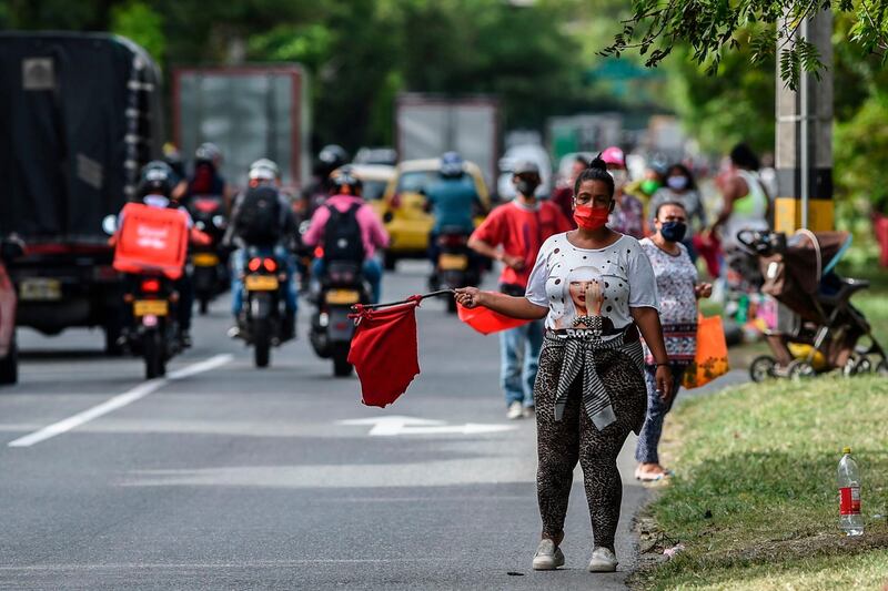 A woman waves a red cloth indicating she needs food, at a highway in Medellin, Colombia during the novel coronavirus, COVID-19, pandemic. AFP