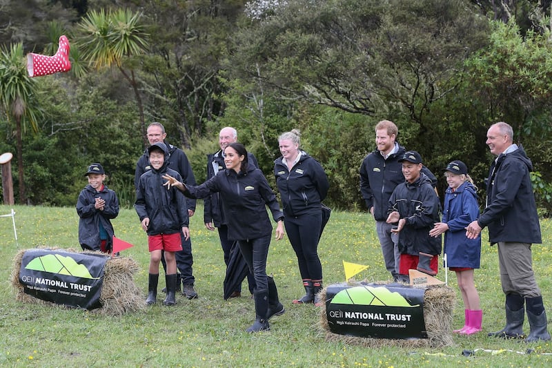 Prince Harry and Meghan join children from the Trees in Survival group during the gumboot throwing contest. EPA
