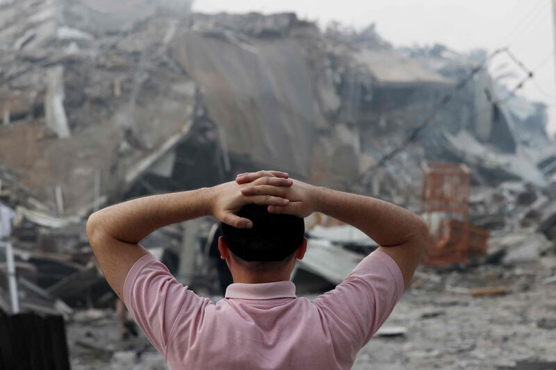 A Palestinian man stands in front of the rubble of Gaza city's Al-Watan Tower, which was destroyed in Israeli airstrikes.  AFP