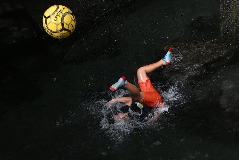 A boy plays with a football on a warm day at the El Cuilio pool in El Salvador. AFP