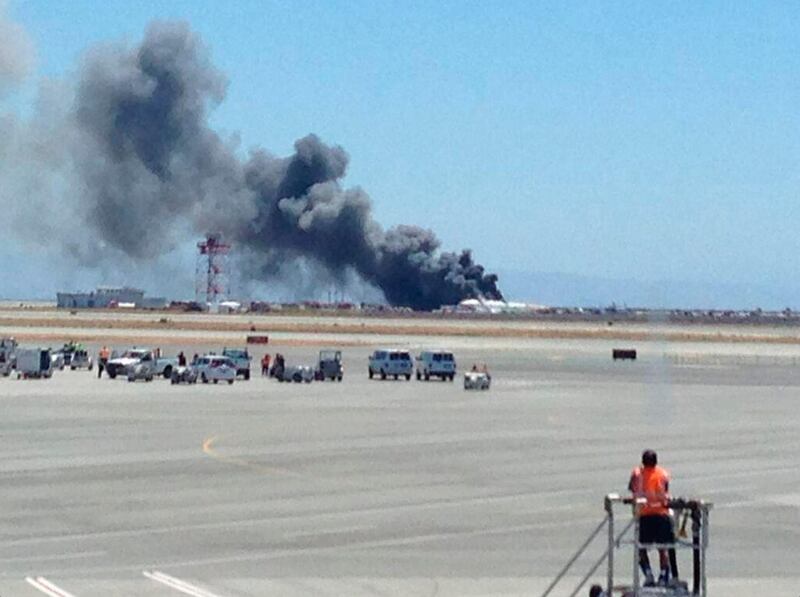 An airport worker looks over at the smoke rising from an Asiana Airlines Boeing 777 after it crashed while landing at San Francisco International Airport in San Francisco, California in this July 6, 2013 handout photo. An Asiana Airlines Boeing 777 flying from Seoul crashed while landing on Saturday at San Francisco International Airport, the U.S. Federal Aviation Administration said. FAA spokesman Lynn Lunsford said it was flight No. 214, and she said it was unclear how many people were on board. REUTERS/Krista Seiden/Handout   (UNITED STATES - Tags: TRANSPORT DISASTER) ATTENTION EDITORS - NO SALES. NO ARCHIVES. FOR EDITORIAL USE ONLY. NOT FOR SALE FOR MARKETING OR ADVERTISING CAMPAIGNS. THIS IMAGE HAS BEEN SUPPLIED BY A THIRD PARTY. IT IS DISTRIBUTED, EXACTLY AS RECEIVED BY REUTERS, AS A SERVICE TO CLIENTS *** Local Caption ***  TOR105_USA-CRASH-AS_0706_11.JPG
