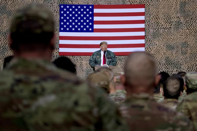 FILE - In this Dec. 26, 2018, file photo, President Donald Trump speaks to members of the military at a hangar rally at Al Asad Air Base, Iraq. President Donald Trump tells troops serving in Iraq that he got them their first pay raise in 10 years and itâ€™s a big one. No, and not exactly. (AP Photo/Andrew Harnik, File)