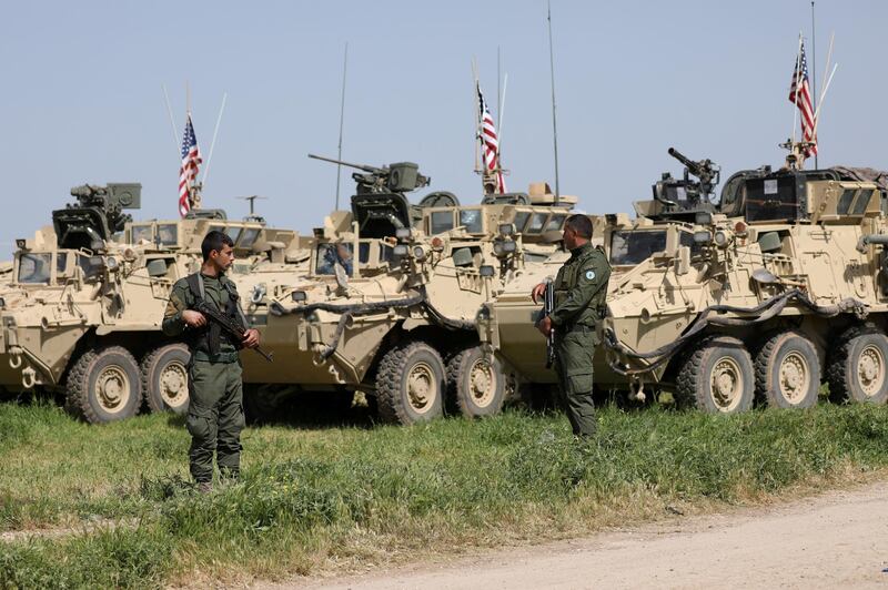 FILE PHOTO:Kurdish fighters from the People's Protection Units (YPG) stand near U.S military vehicles in the town of Darbasiya next to the Turkish border, Syria April 29, 2017. REUTERS/Rodi Said/File Photo