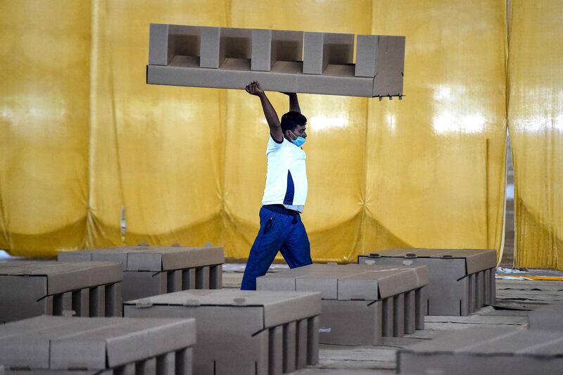 A worker carrying a cardboard bed inside the campus hall of spiritual organisation Radha Soami Satsang Beas (RSSB) which is being converted into a 10,000 beds COVID-19 coronavirus care centre in New Delhi.  AFP