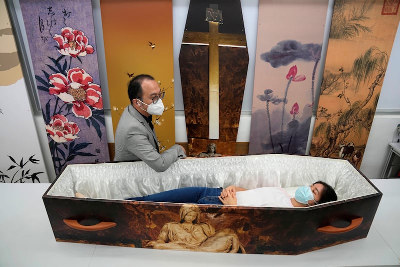 Wilson Tong, left, chief executive of LifeArt Asia, talks to a reporter trying out a paper coffin at his factory in Hong Kong. Hong Kong is running short of coffins during its deadliest outbreak of the coronavirus pandemic. All photos by AP