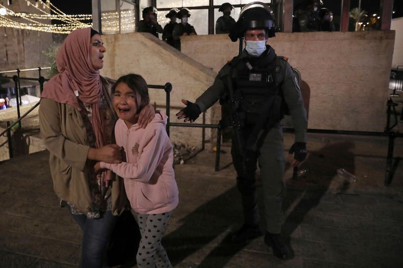 An Israeli police officer gestures to a Palestinian woman and her daughter, frightened by clashes outside of the Damascus Gate to the Old City of Jerusalem. AP Photo