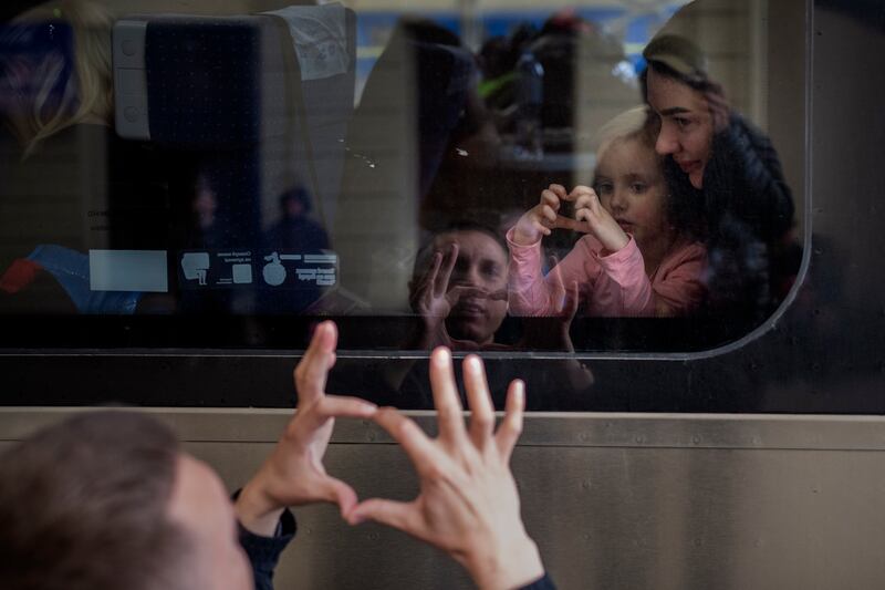 Ukrainian Nicolai, 41, says goodbye to his daughter Elina, 4, and his wife Lolita on a train in Lviv, western Ukraine, bound for Poland. AP Photo