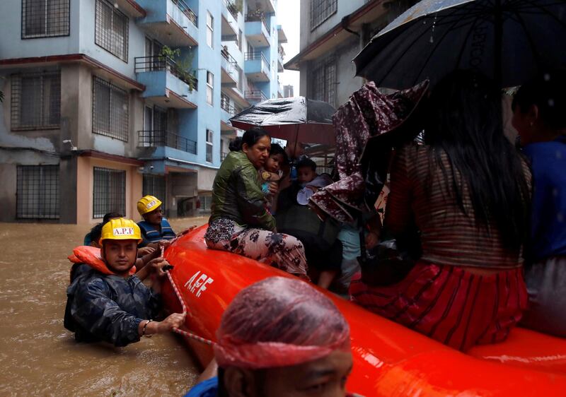 A woman carrying a child is moved by rescue workers towards dry ground from a flooded colony in Kathmandu, Nepal July 12, 2019. REUTERS/Navesh Chitrakar