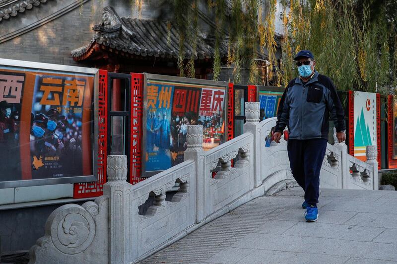 A man wearing a face mask to help curb the spread of the coronavirus takes a morning walk passing by posters tribute to the medical workers in different provincial on the frontlines against the COVID-19 on display at a park in Beijing. AP Photo