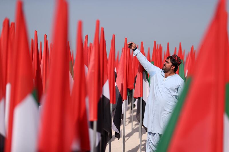DUBAI, UNITED ARAB EMIRATES - NOVEMBER 25:  A man takes a selfie infront of UAE flags on November 25, 2020 in Dubai, United Arab Emirates. The country's government recently decreed that foreigners can fully own local firms, a change from previous law that required foreign investors to have an Emirati partner with at least a 51% stake in the company. Several types of businesses were excluded from the new law, such as those in the energy, telecommunications and transport sectors. (Photo by Francois Nel/Getty Images)