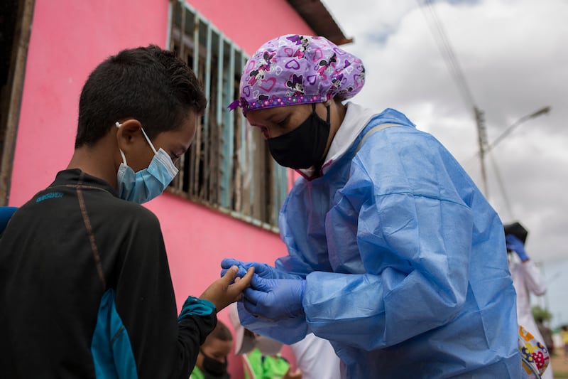A medical volunteer of the Doctors Without Borders (MSF) organization takes a blood sample from a patient to be tested for malaria at his home in Barcelona, Venezuela. AFP