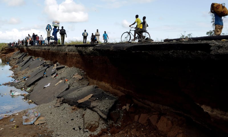 Pedestrians walk on the edge of a collapsed bridge in Nhamatanda. AP Photo