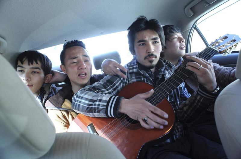 Members of an Afghan band Tanin, Mahmoud Hejran (2nd left) and Zabih Hosseini (centre) play the guitar and sing as they travel back to their music studio after performing on a live TV programme.