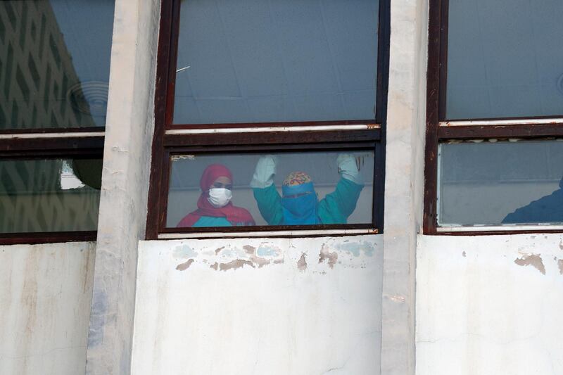 epa09094620 Yemeni nurses wearing protective face masks look out from a window of a hospital amid concerns over the coronavirus COVID-19 pandemic, in Sana’a, Yemen, 24 March 2021. COVID-19 infection numbers continues to increase, in a country that with six years of civil war, left its healthcare system in shambles.  EPA/YAHYA ARHAB