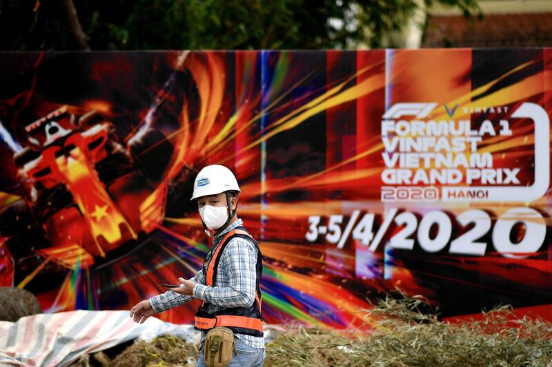 (FILES) In this file photo taken on March 10, 2020, a worker, wearing a facemask amid concerns of the Covid-19 coronavirus outbreak, walks past hoarding at the Formula One Vietnam Grand Prix race track site in Hanoi. Vietnam's first Formula One Grand Prix has been dropped from the 2021 calendar, according to a November 10, 2020 report on the BBC. The move had been triggered on the arrest on corruption charges of a key official responsible for the race in Hanoi, it added. / AFP / Manan VATSYAYANA
