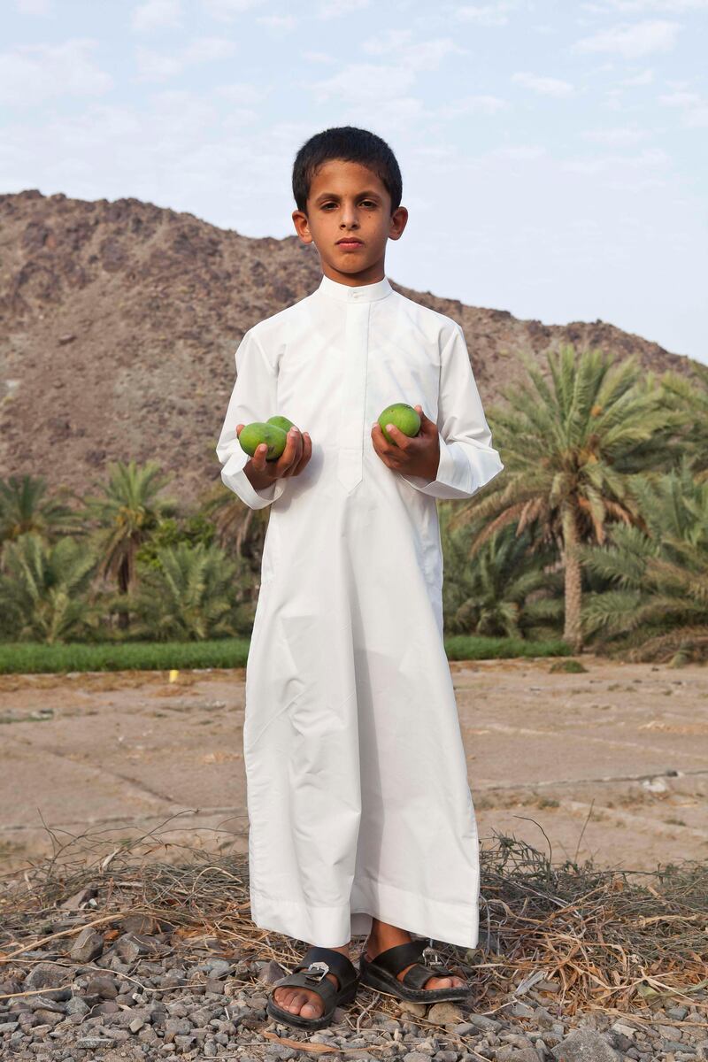June 17, Mohammad Khalifa poses for the camera with some locally grown mangoes on a traditional Emirate farm in Wadi Al Tuwa.  June 1, Ras Al Khaimah, United Arab Emirates. (Photo: Antonie Robertson/ The National)