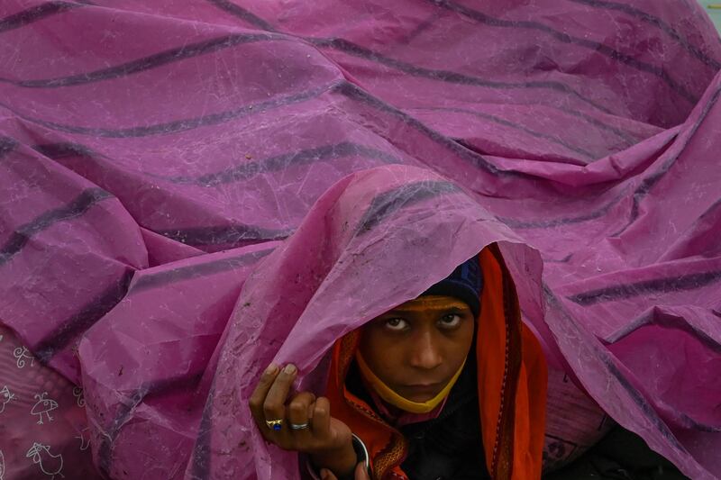 A boy uses a plastic sheet to shelter from rain at the Gangasagar Mela on the occasion of Makar Sankranti at Sagar Island. AFP