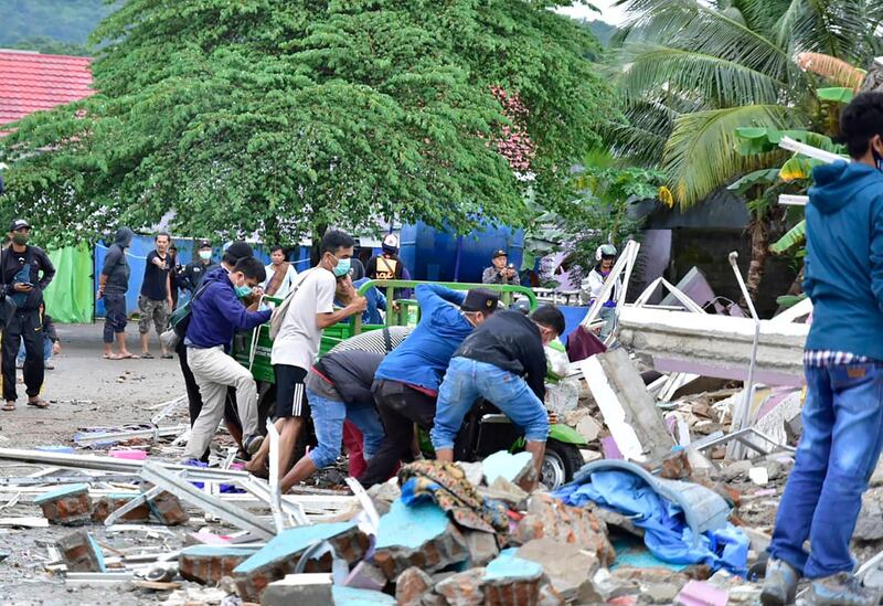 Rescuers search for survivors at a collapsed building in Mamuju city. AFP