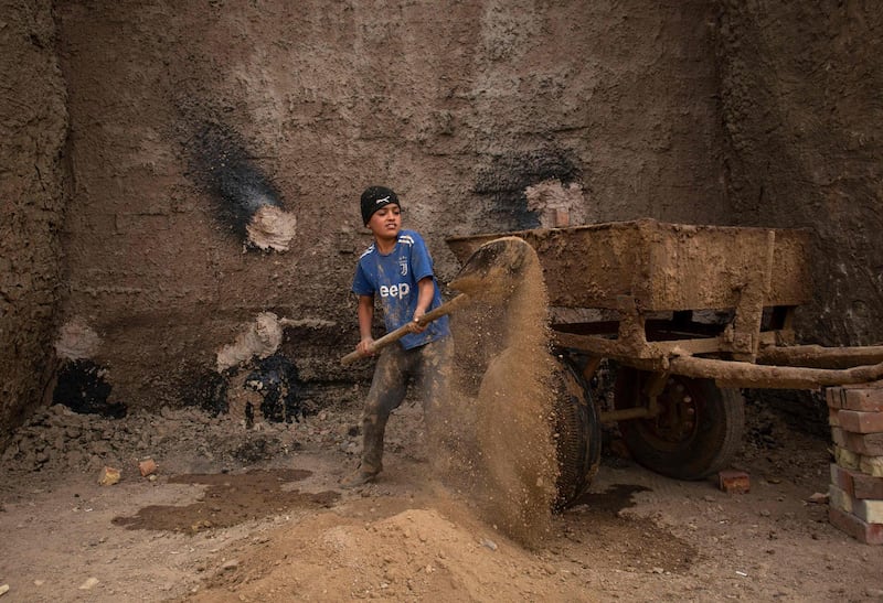 A worker fills a donkey cart with soil to make bricks.  AFP