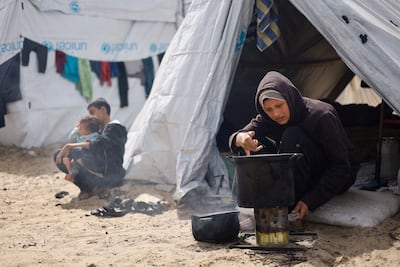 A displaced Palestinian woman cooks in Rafah in the southern Gaza Strip. Reuters