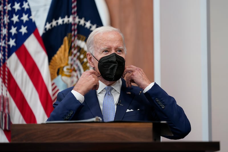 US President Joe Biden removes his face mask as he arrives to speak about the economy during a meeting at the White House in Washington. AP