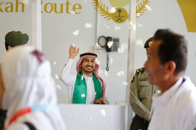 A Saudi airport worker throws flowers as he welcomes Malaysian pilgrims at the Hajj Terminal at Jiddah airport, Saudi Arabia, Saturday, Aug. 3, 2019.  The annual Islamic pilgrimage draws millions of visitors each year, making it the largest yearly gathering of people in the world.  (AP Photo/Amr Nabil)