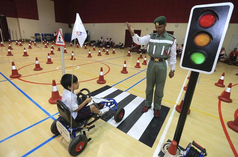 Rayyan Ramtoola, 6, gets the green light from Dubai Police officer Salahdeen Mohammed to proceed on the simulation road after waiting at the traffic signal at Gems Royal Dubai School. Sarah Dea / The National