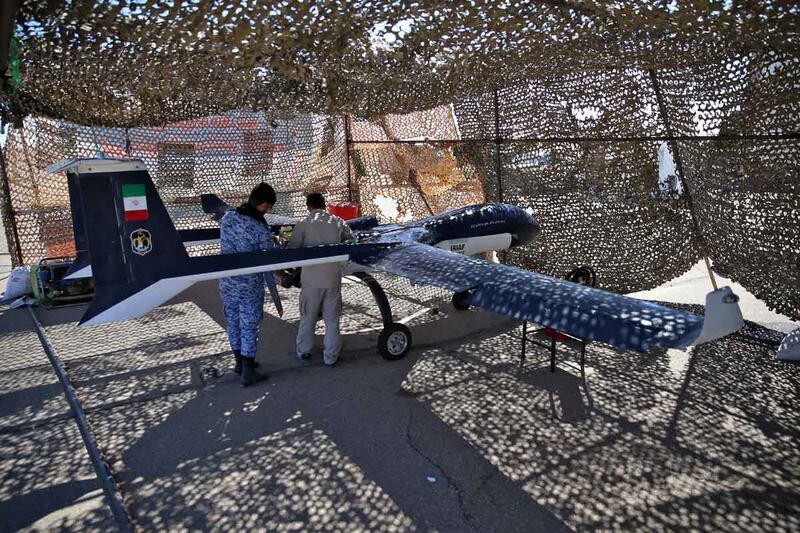 Technicians inspect a military vehicle in a camouflage enclosure. AFP