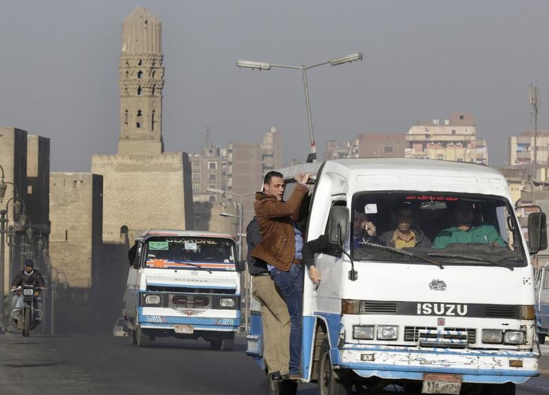 Egyptians hang out of a microbus in front of the ancient gates of the historical Fatimid Cairo. Amr Nabil/AP Photo