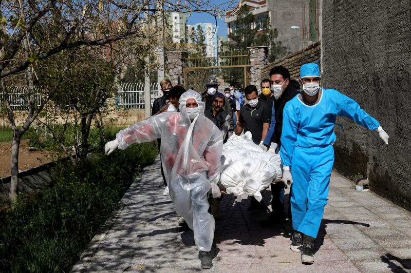 People wearing protective clothing carry the body of a victim who died after being infected with the new coronavirus at a cemetery just outside Tehran, Iran, March 30, 2020. The new coronavirus causes mild or moderate symptoms for most people, but for some, especially older adults and people with existing health problems, it can cause more severe illness or death. (AP Photo/Ebrahim Noroozi)