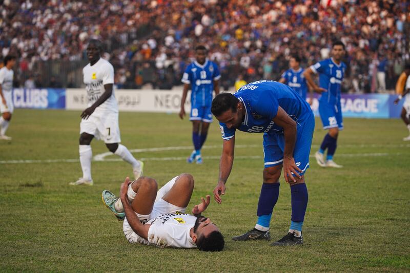 An Ittihad player lies injured on the field against Air Force Club. 