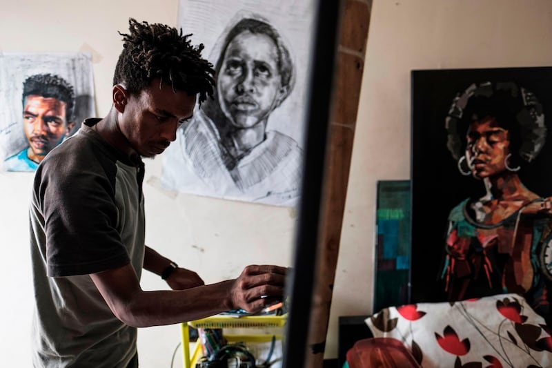 Eritrean artist Nebay Abraha, 23, working on a painting in his room and studio in Addis Ababa. AFP