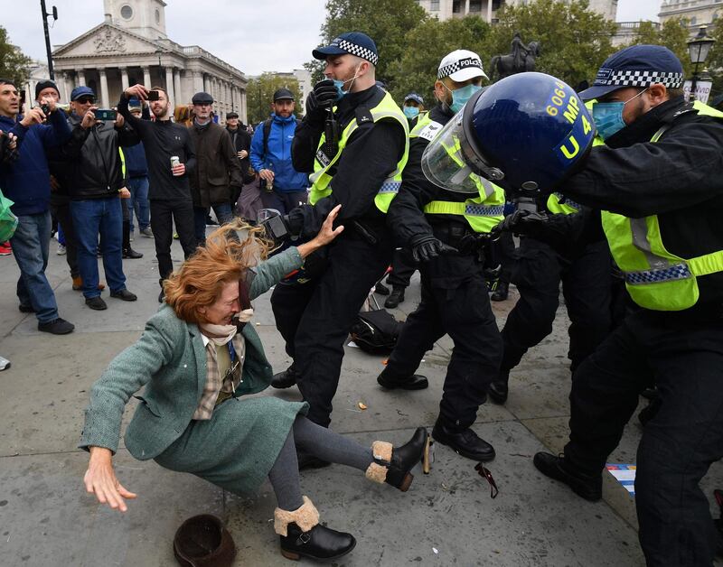 A woman falls as police move in to disperse protesters in Trafalgar Square in London, at a 'We Do Not Consent!' mass rally against vaccination and government restrictions designed to fight the spread of the coronavirus, including the wearing of masks and taking tests for the virus. AFP