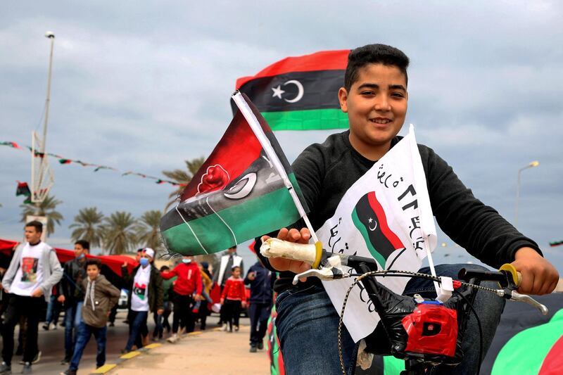 A boy rides a bicycle decorated with flags through Tripoli as the country celebrates the 10th anniversary of the uprising. AFP