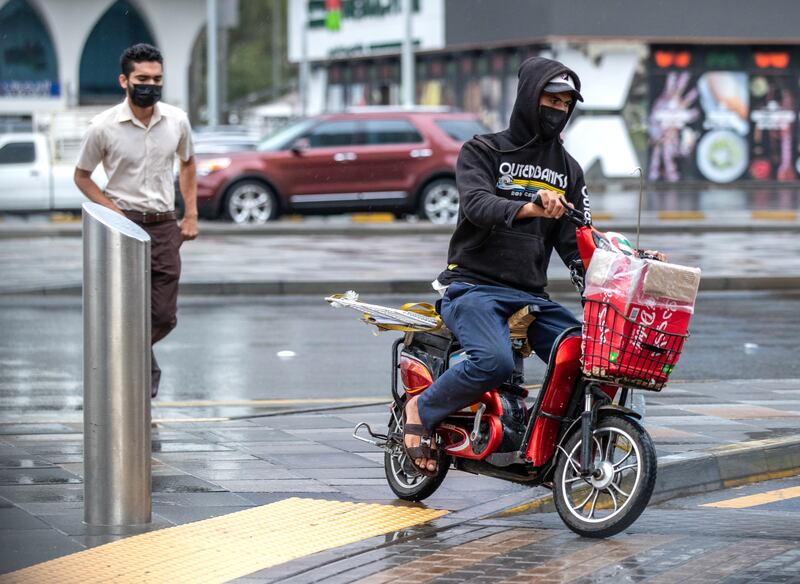A man rides an electric bike in the rain. Victor Besa / The National